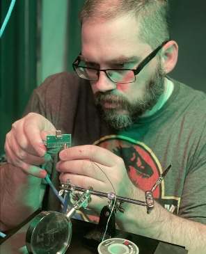 Soldering a circuit board at the bench, held in a helping-hands tool